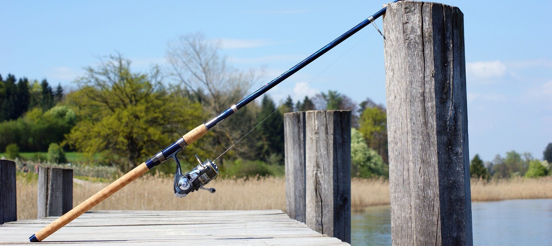 A fishing pole leaning on a piling attached to a pier.