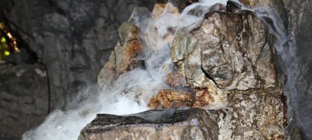 Image shows a rock formation inside a cave with water and fog.