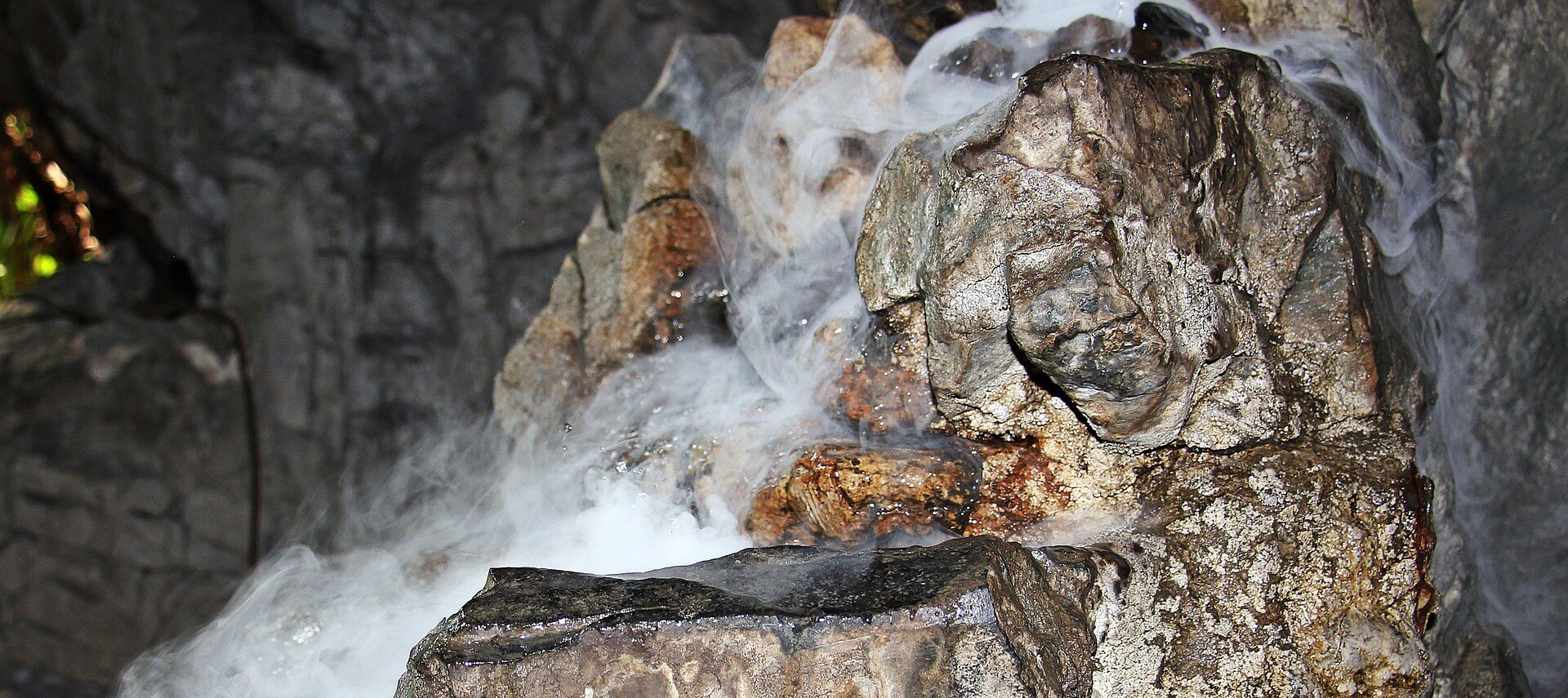 Image shows a rock formation inside a cave with water and fog.