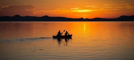 Image of a kayak on a calm lake at sunset