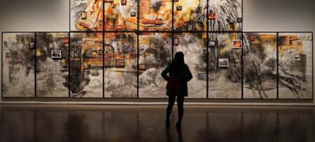 Image of a woman looking at art hanging on a wall in a museum.